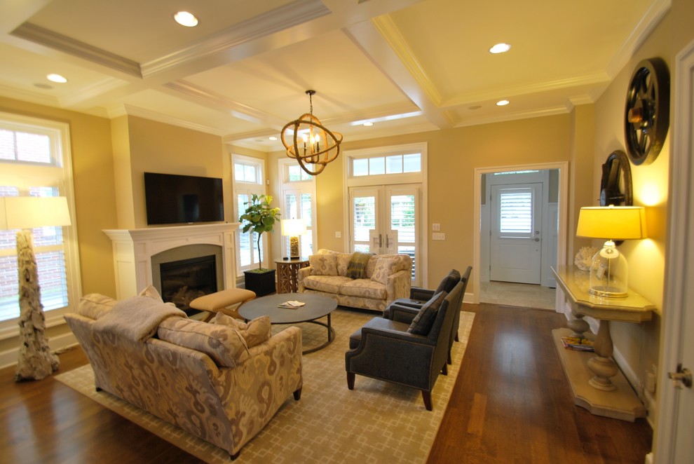 This is an example of a medium sized traditional open plan living room in DC Metro with beige walls, dark hardwood flooring, a standard fireplace, a stone fireplace surround, a wall mounted tv and brown floors.