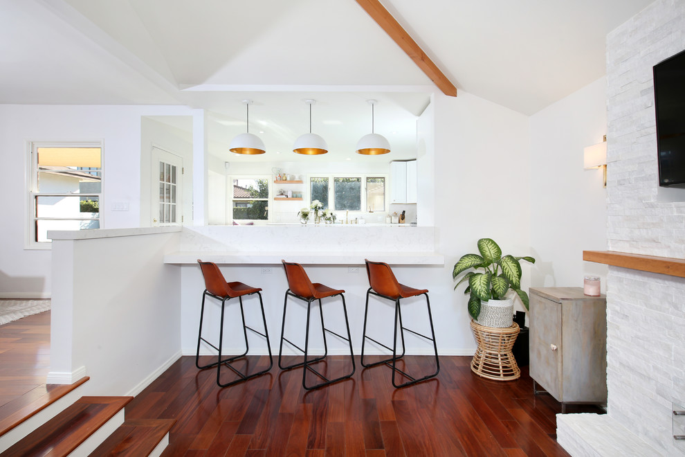Geräumiges Modernes Wohnzimmer mit weißer Wandfarbe, braunem Holzboden, Kamin, Kaminumrandung aus Stein und braunem Boden in Los Angeles