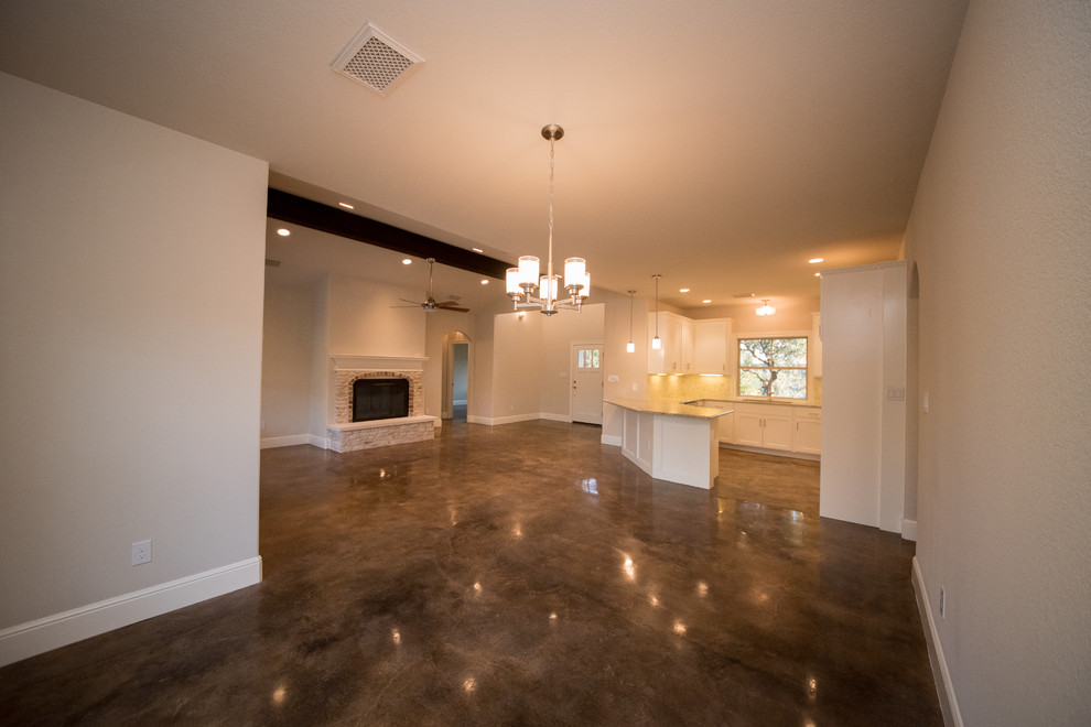Großes, Offenes Rustikales Wohnzimmer mit Betonboden, beiger Wandfarbe, Kamin und Kaminumrandung aus Stein in Austin