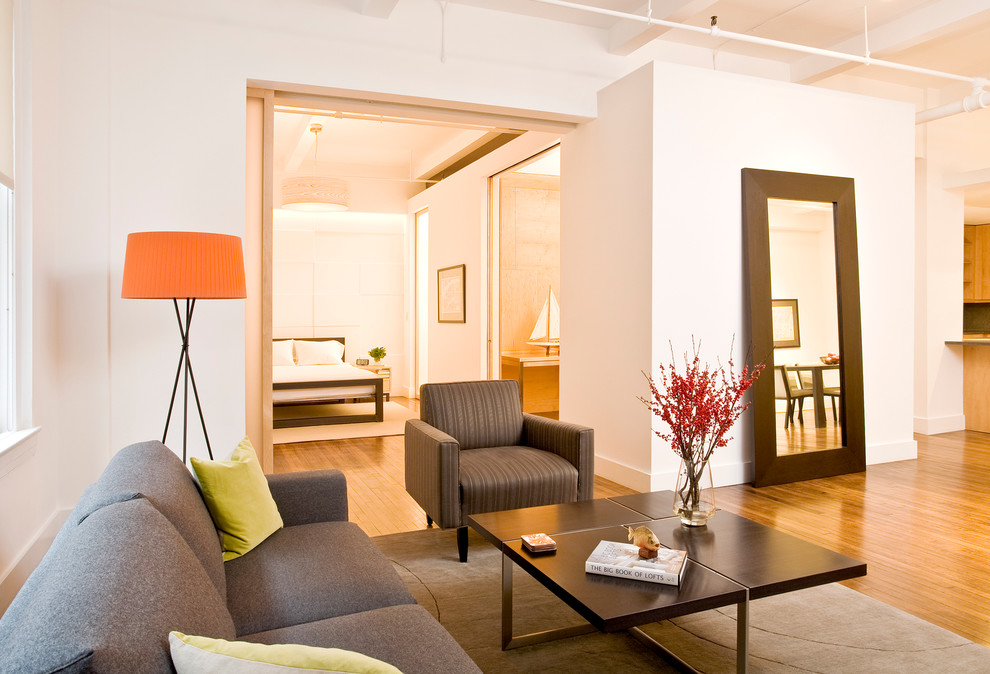 Großes Modernes Wohnzimmer ohne Kamin mit weißer Wandfarbe, braunem Holzboden und TV-Wand in New York