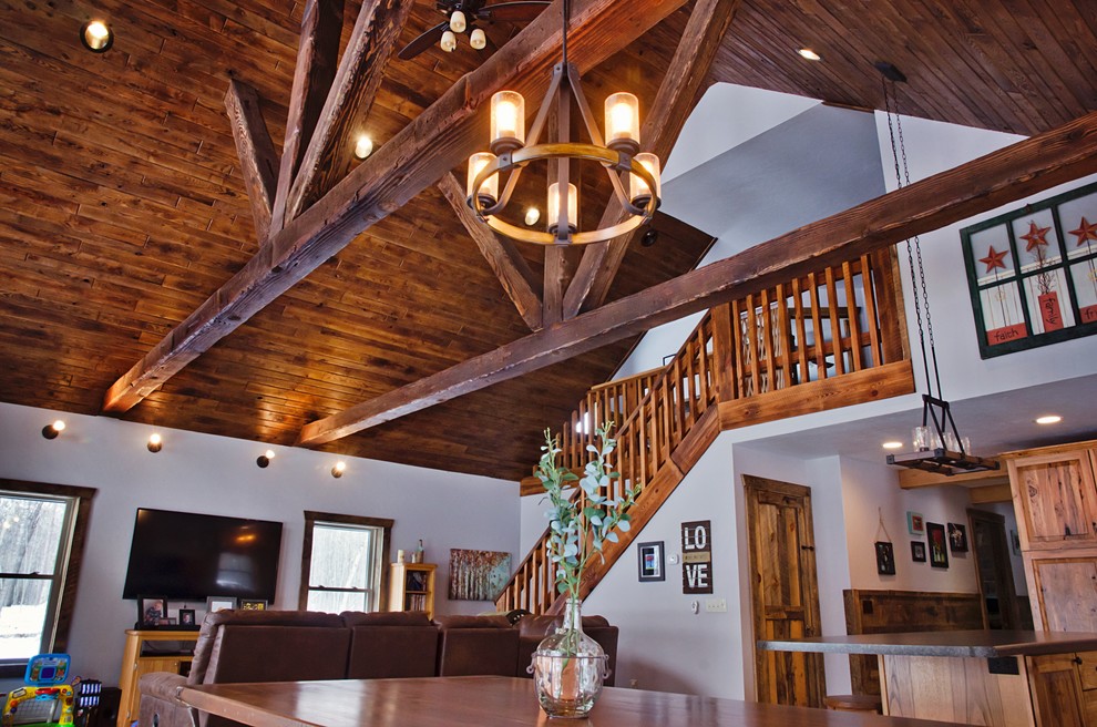 Diseño de salón abierto rústico grande sin chimenea con paredes blancas, suelo de madera en tonos medios y suelo marrón