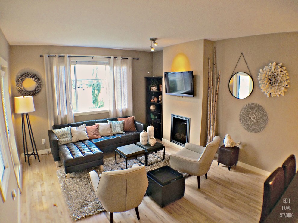 Cette photo montre un petit salon tendance ouvert avec un mur beige, un sol en bois brun, une cheminée standard et un téléviseur fixé au mur.