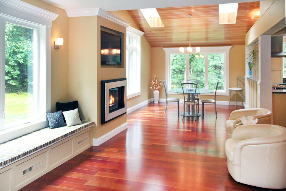 Réalisation d'un grand salon tradition ouvert avec un mur beige, un sol en bois brun, une cheminée standard, un manteau de cheminée en métal, un téléviseur encastré et un sol rouge.