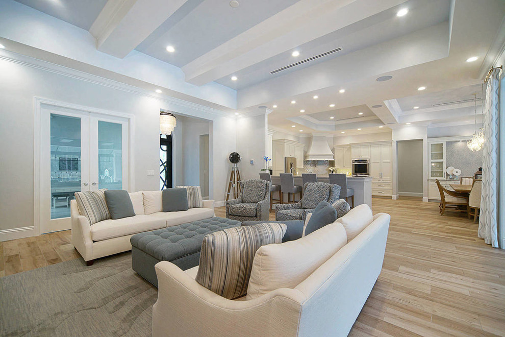 Idée de décoration pour un grand salon marin ouvert avec un mur gris, parquet clair et un sol beige.