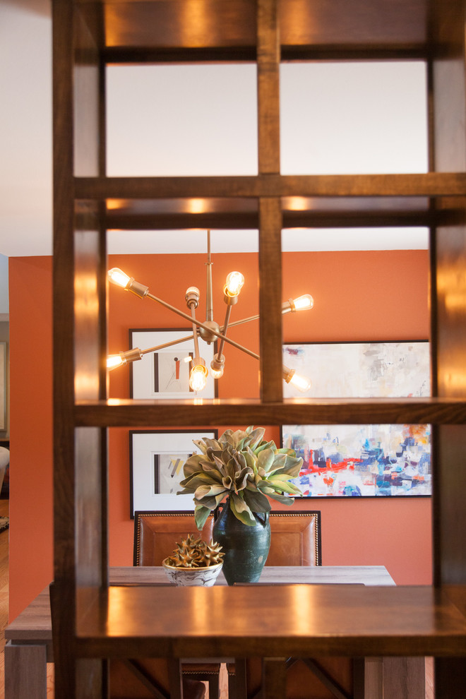 Immagine di un soggiorno minimal di medie dimensioni e aperto con pareti arancioni, pavimento in legno massello medio, camino bifacciale e cornice del camino in pietra