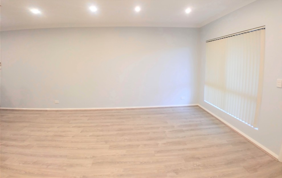 Modelo de salón abierto actual grande con paredes blancas, suelo laminado y suelo beige