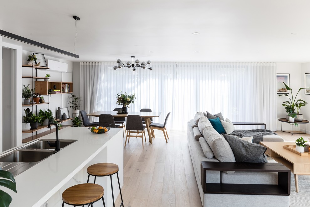 Cette image montre un salon minimaliste de taille moyenne et ouvert avec un mur blanc, sol en stratifié, un téléviseur encastré et un sol marron.