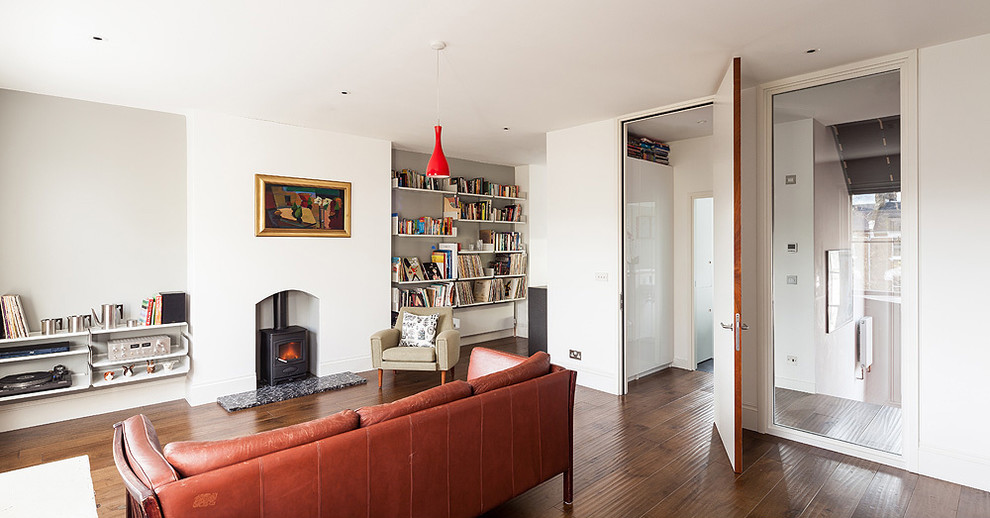 This is an example of a large contemporary open plan living room in London with grey walls, medium hardwood flooring, a wood burning stove and no tv.
