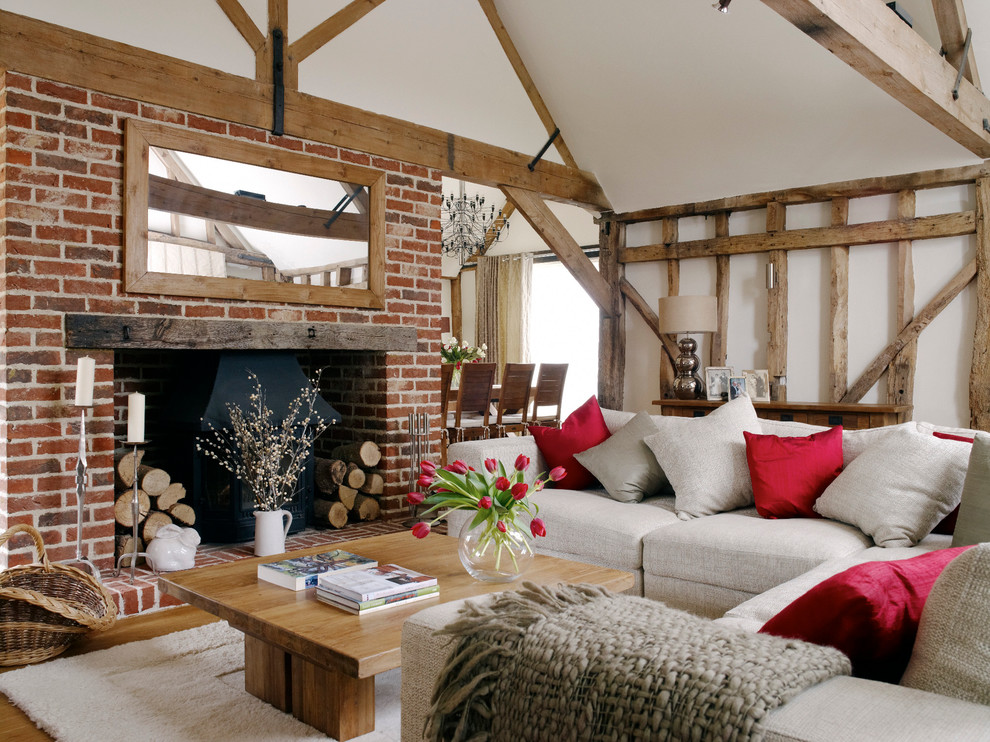 Ejemplo de salón para visitas de estilo de casa de campo con paredes blancas, suelo de madera en tonos medios, todas las chimeneas y marco de chimenea de ladrillo
