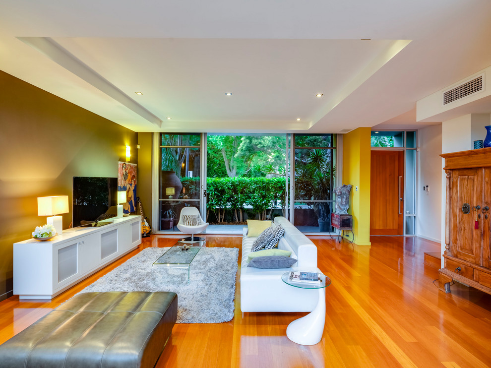 Источник вдохновения для домашнего уюта: огромная открытая гостиная комната в стиле модернизм с разноцветными стенами, светлым паркетным полом, отдельно стоящим телевизором и коричневым полом