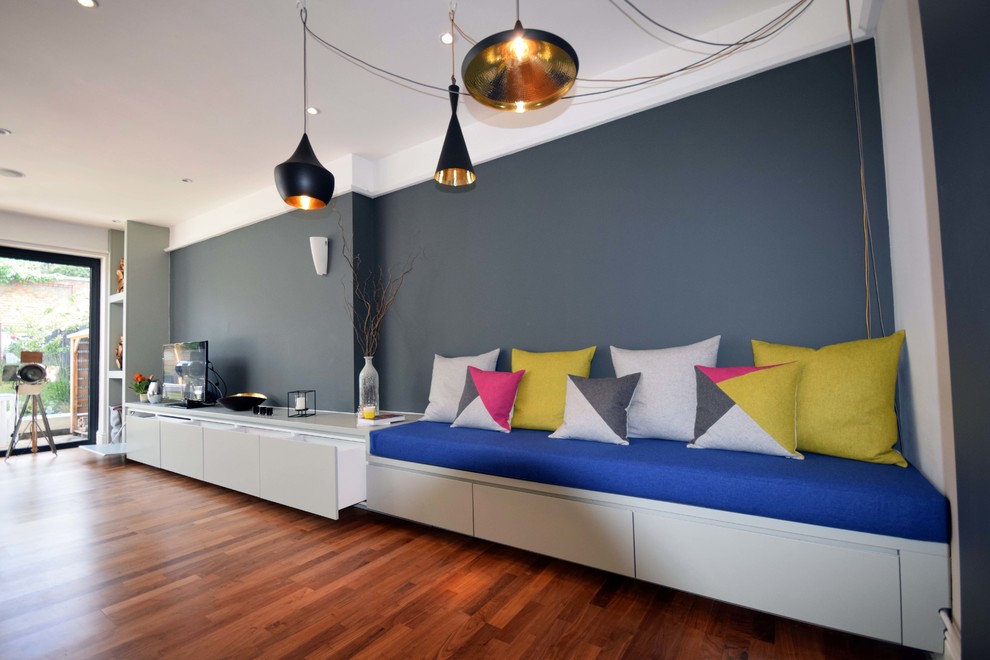 ロンドンにある広いコンテンポラリースタイルのおしゃれなLDK (グレーの壁、ラミネートの床、薪ストーブ、据え置き型テレビ、茶色い床) の写真