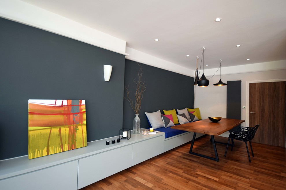 Источник вдохновения для домашнего уюта: большая открытая гостиная комната в современном стиле с серыми стенами, полом из ламината, печью-буржуйкой, отдельно стоящим телевизором и коричневым полом