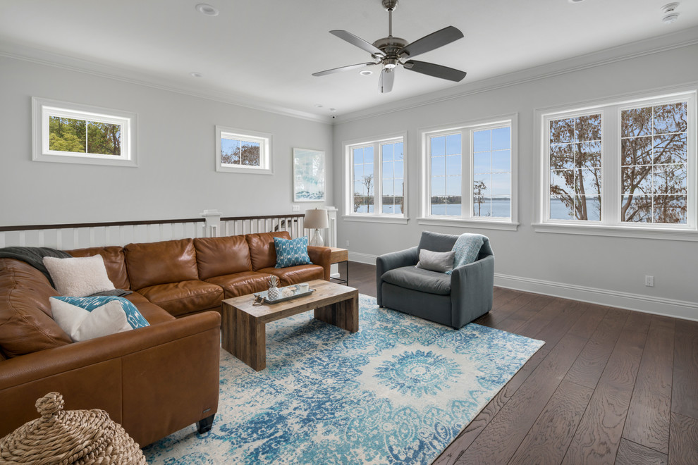 Large nautical enclosed living room in Orlando with grey walls, dark hardwood flooring, no fireplace, a wall mounted tv, brown floors and feature lighting.