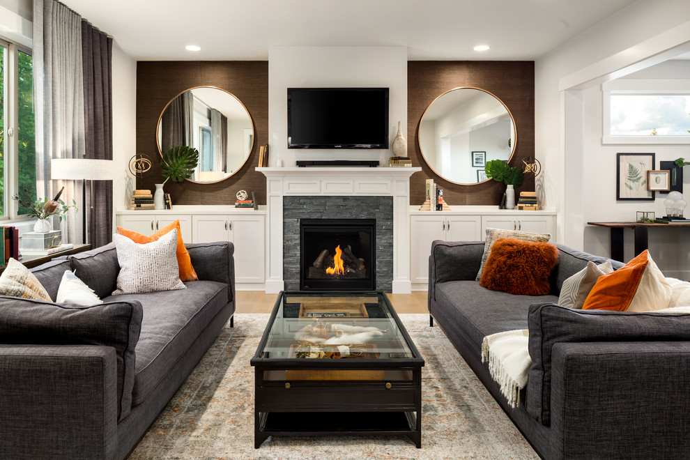 Стильный дизайн: гостиная комната в стиле неоклассика (современная классика) с коричневыми стенами, паркетным полом среднего тона, стандартным камином, фасадом камина из камня и коричневым полом - последний тренд