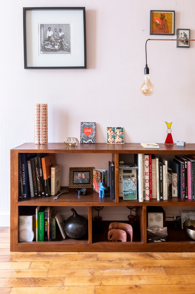 Cette image montre un salon minimaliste de taille moyenne et fermé avec un mur rose, un sol en bois brun, aucun téléviseur et un sol beige.