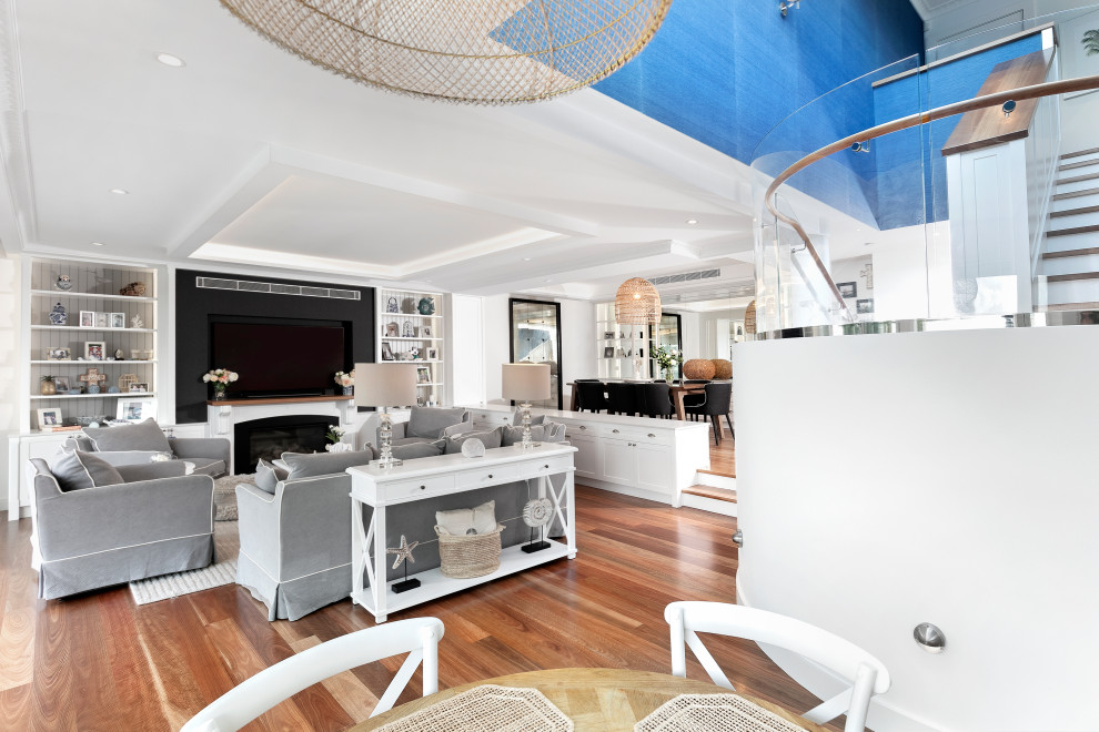 Großes, Offenes Maritimes Wohnzimmer mit weißer Wandfarbe, braunem Holzboden, Kamin, Kaminumrandung aus Stein, Multimediawand, eingelassener Decke und vertäfelten Wänden in Sydney