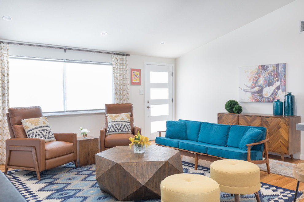 Kleines, Offenes Retro Wohnzimmer mit blauer Wandfarbe, braunem Holzboden, Kamin, Kaminumrandung aus Backstein und braunem Boden in Orange County