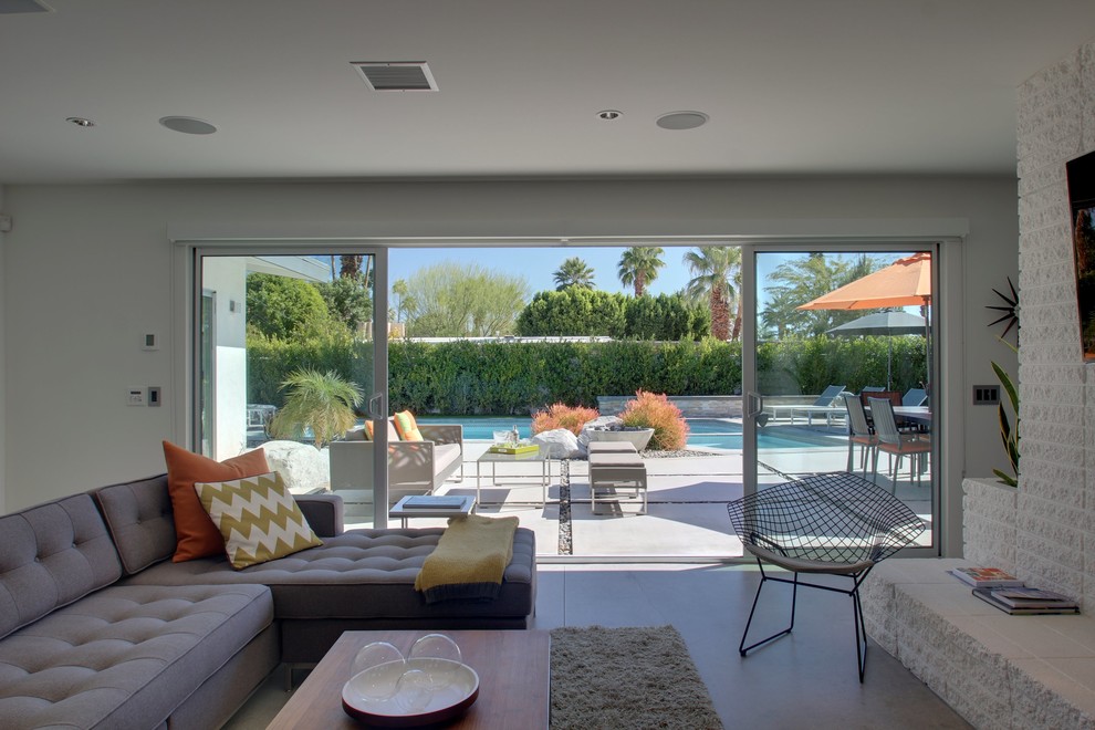 Living room - mid-sized contemporary open concept concrete floor living room idea in Los Angeles with white walls, a two-sided fireplace, a brick fireplace and a wall-mounted tv
