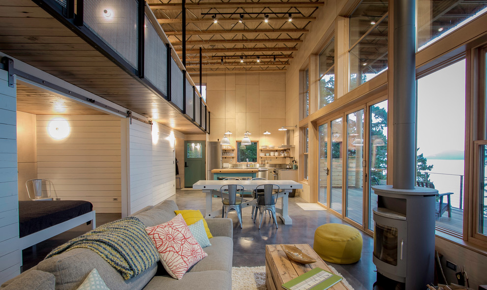 На фото: большая двухуровневая гостиная комната в стиле лофт с бежевыми стенами, бетонным полом, печью-буржуйкой и фасадом камина из металла