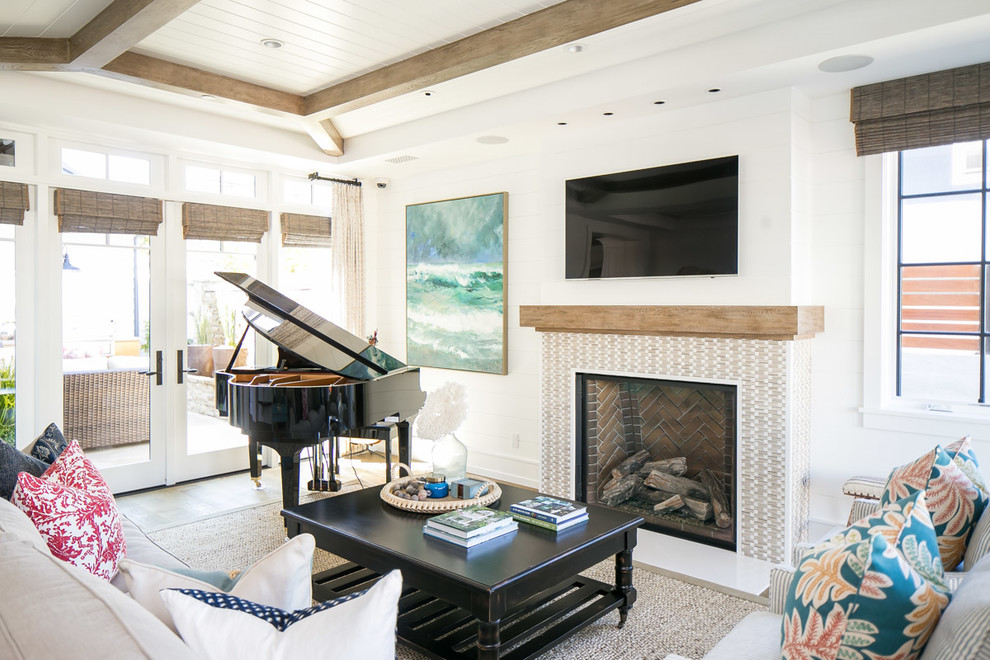 This is an example of a large world-inspired open plan living room in Orange County with white walls, medium hardwood flooring, a standard fireplace, a tiled fireplace surround, a wall mounted tv and brown floors.