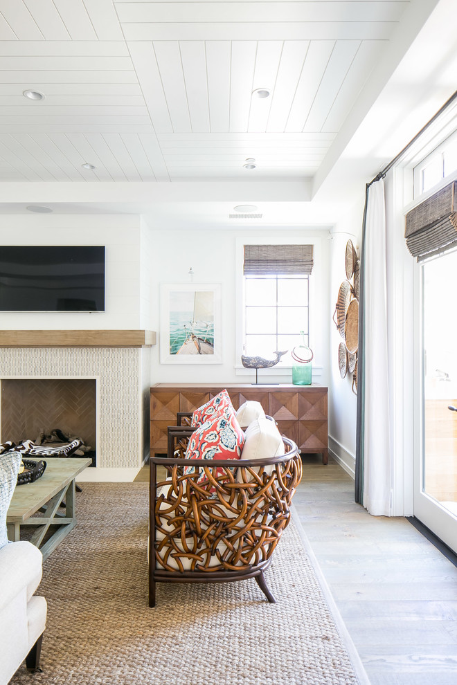 Example of a large island style open concept medium tone wood floor and brown floor living room design in Orange County with white walls, a standard fireplace, a tile fireplace and a wall-mounted tv