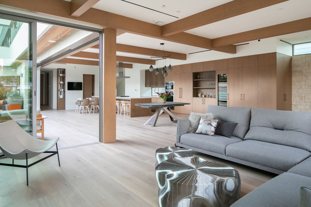 Diseño de salón abierto contemporáneo con paredes blancas, suelo de madera clara, suelo beige y vigas vistas