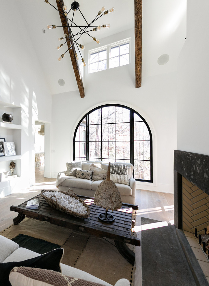 Foto de salón actual sin televisor con paredes blancas, suelo de madera clara, todas las chimeneas y marco de chimenea de piedra