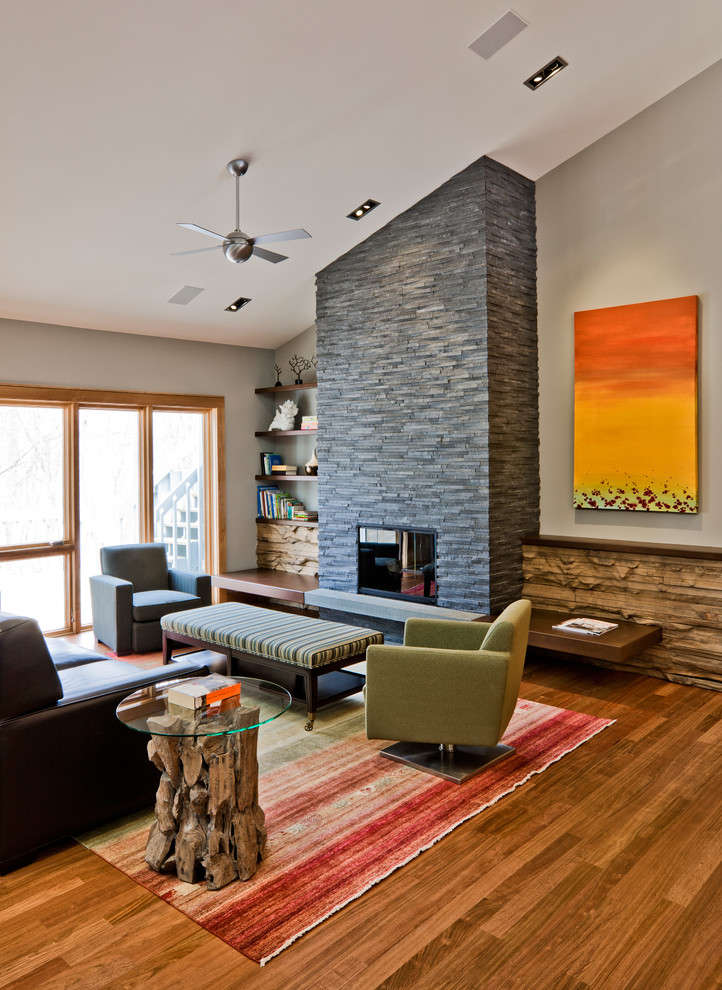 Foto de salón actual con paredes grises, marco de chimenea de piedra y alfombra