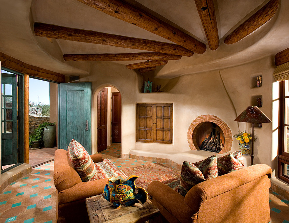 フェニックスにあるラグジュアリーなサンタフェスタイルのおしゃれなリビング (ベージュの壁、テラコッタタイルの床、標準型暖炉、漆喰の暖炉まわり) の写真