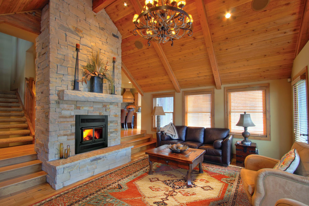 Exemple d'un grand salon craftsman ouvert avec une salle de réception, un mur beige, parquet clair, une cheminée standard, un manteau de cheminée en pierre et un sol marron.