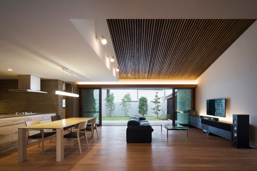Esempio di un soggiorno minimal aperto con pareti bianche, pavimento in legno massello medio, TV a parete e pavimento beige