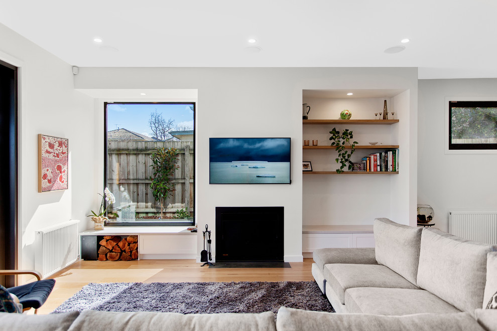 Ispirazione per un soggiorno costiero con pareti bianche, pavimento in legno massello medio, camino classico, TV a parete e pavimento marrone