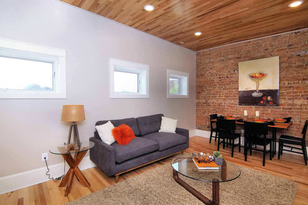 Foto de salón abierto tradicional renovado de tamaño medio sin chimenea con paredes grises, suelo de madera clara, televisor colgado en la pared y suelo marrón