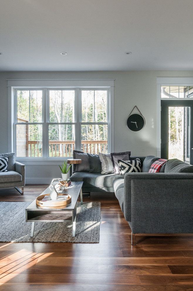 Mittelgroßes, Offenes Wohnzimmer mit grauer Wandfarbe, braunem Holzboden und Gaskamin in Toronto