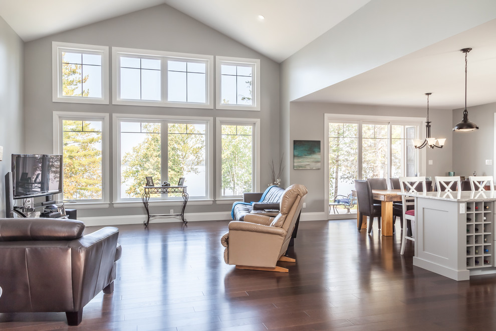 Medium sized classic open plan living room in Ottawa with grey walls, dark hardwood flooring, a standard fireplace, a stone fireplace surround, a freestanding tv and brown floors.