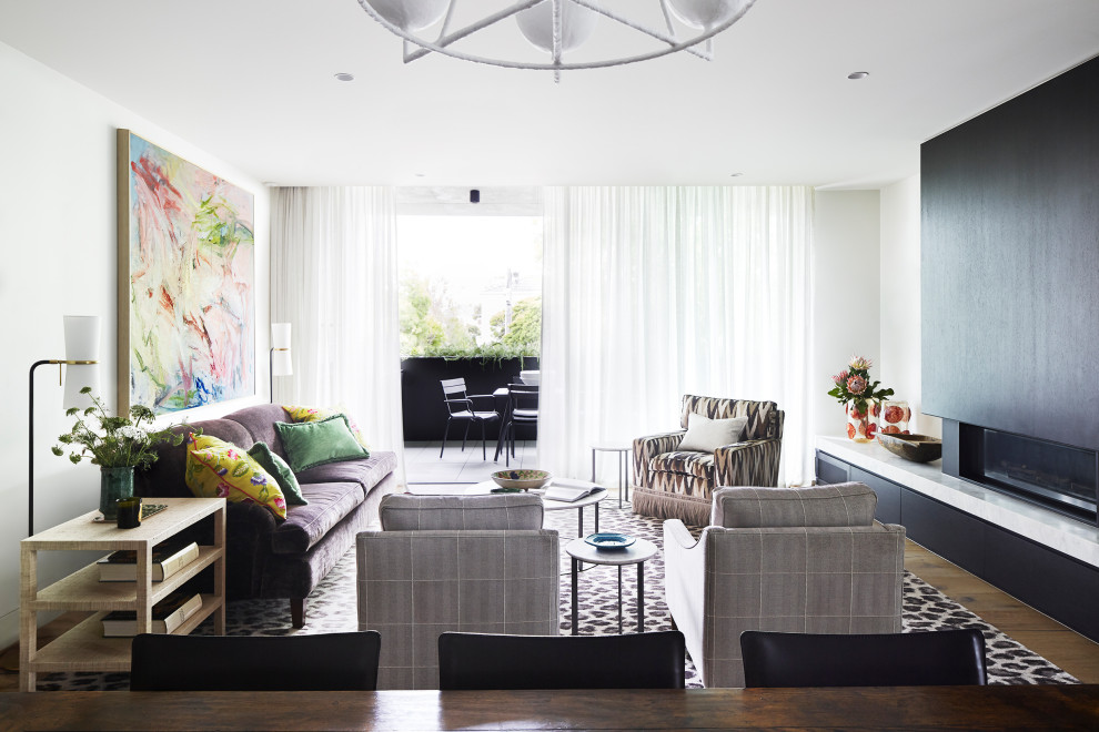 Mittelgroßes, Offenes Modernes Wohnzimmer mit weißer Wandfarbe, TV-Wand, braunem Holzboden, Gaskamin und braunem Boden in Sonstige