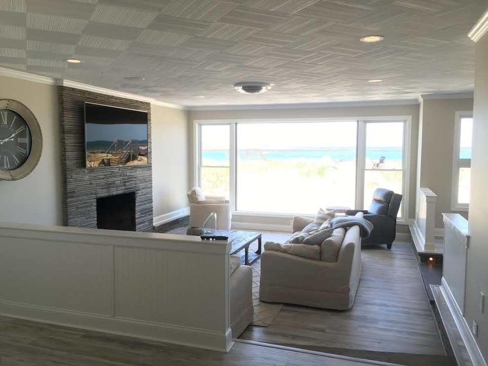 Inspiration for a medium sized beach style formal open plan living room in Boston with a standard fireplace, grey walls, dark hardwood flooring, a stone fireplace surround, a wall mounted tv and grey floors.