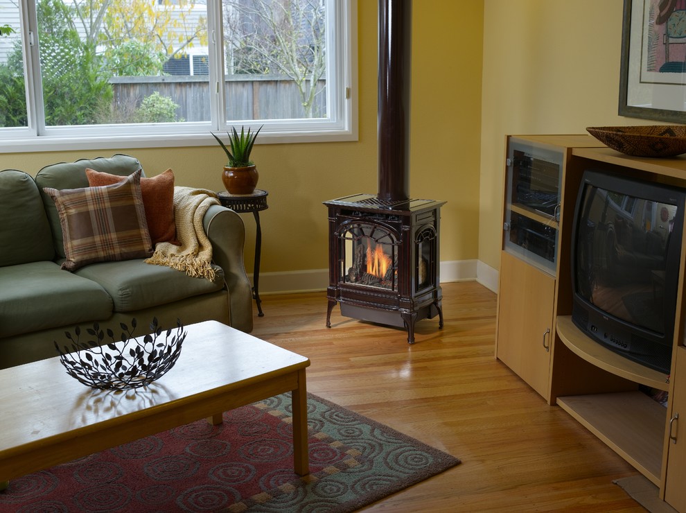シアトルにあるお手頃価格の中くらいなトラディショナルスタイルのおしゃれな独立型リビング (黄色い壁、淡色無垢フローリング、標準型暖炉、金属の暖炉まわり、埋込式メディアウォール、ベージュの床) の写真