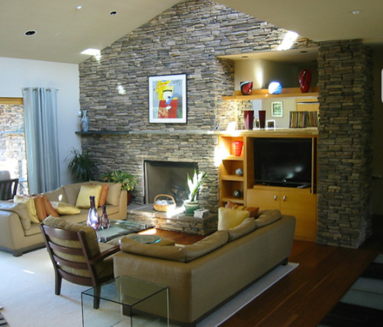Mittelgroßes Wohnzimmer im Loft-Stil mit beiger Wandfarbe, braunem Holzboden und Kaminumrandung aus Stein in Portland
