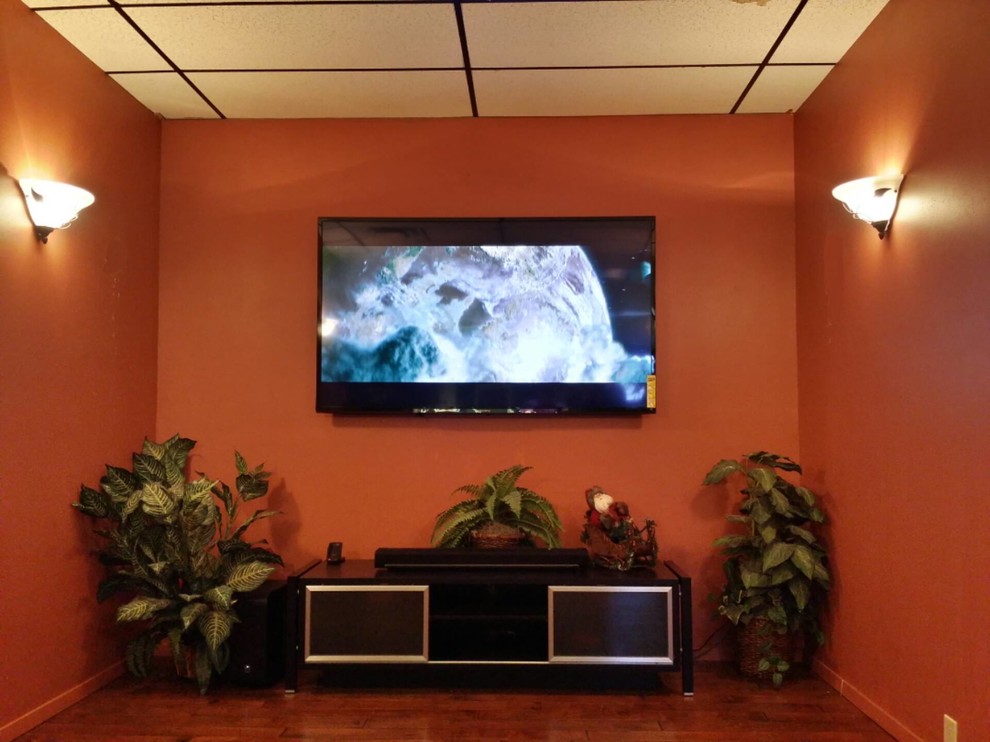 Cette image montre un salon traditionnel de taille moyenne et fermé avec un mur orange, moquette et un téléviseur fixé au mur.