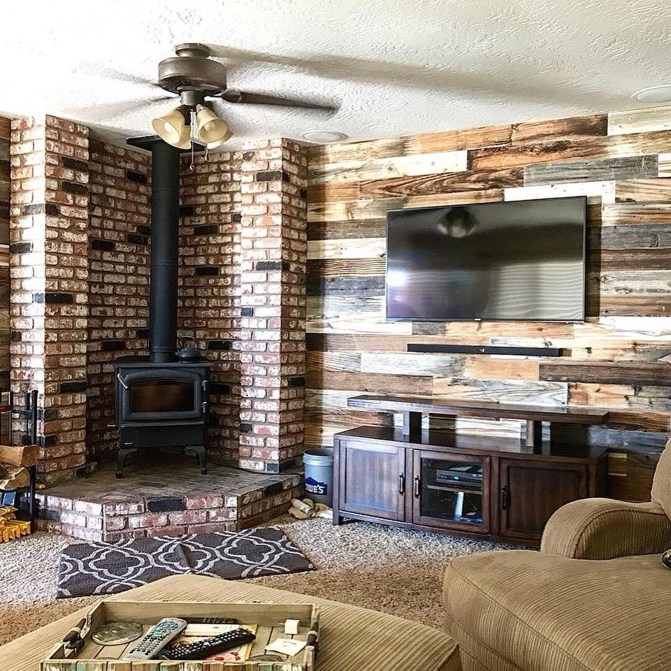 Cette photo montre un grand salon nature fermé avec un mur multicolore, moquette, un poêle à bois, un manteau de cheminée en brique, un téléviseur fixé au mur et un sol beige.