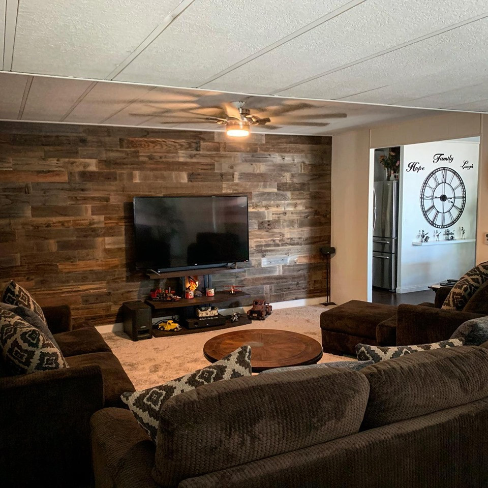 Photo of a large farmhouse enclosed living room in Other with grey walls, carpet, a freestanding tv and grey floors.