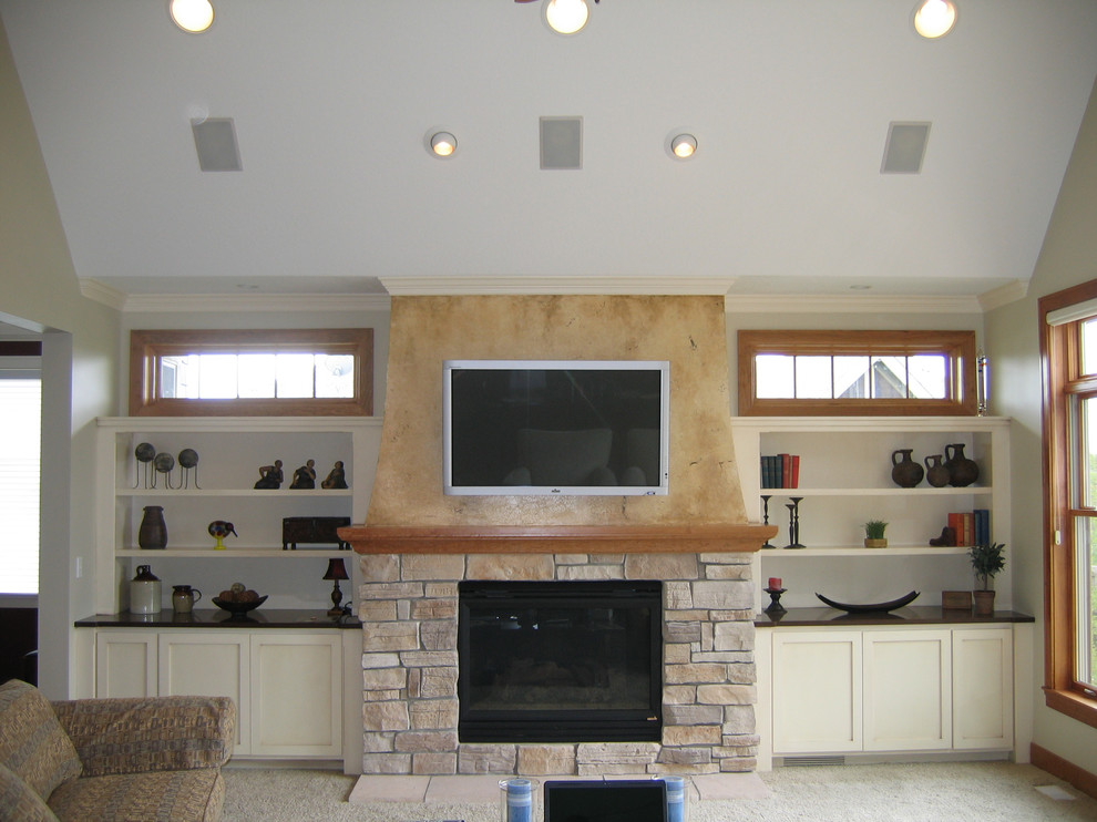 This is an example of a medium sized classic enclosed living room in Minneapolis with beige walls, carpet, a standard fireplace, a stone fireplace surround, a wall mounted tv and grey floors.