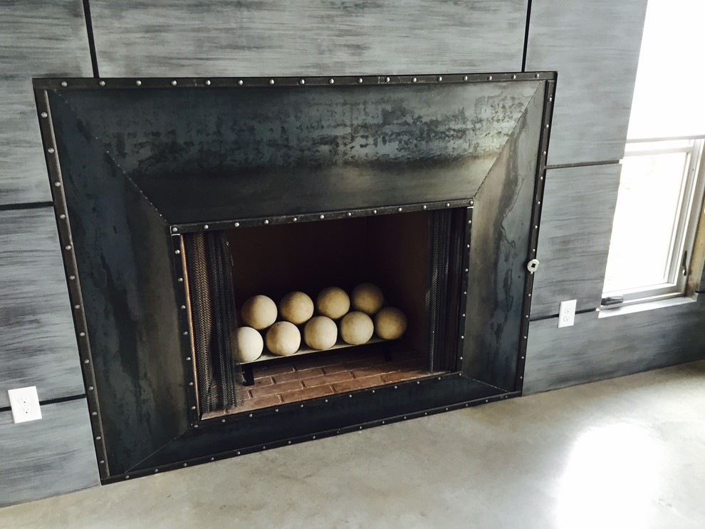 This is an example of a medium sized contemporary formal enclosed living room in Dallas with grey walls, concrete flooring, a standard fireplace and a metal fireplace surround.