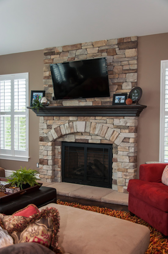 Inspiration for a medium sized traditional enclosed living room in St Louis with brown walls, carpet, a standard fireplace, a stone fireplace surround and a wall mounted tv.
