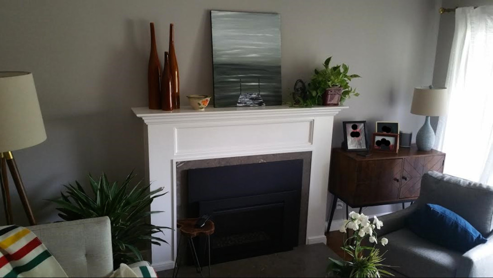 サンフランシスコにあるお手頃価格の中くらいなトラディショナルスタイルのおしゃれなリビング (グレーの壁、無垢フローリング、標準型暖炉、漆喰の暖炉まわり、茶色い床) の写真