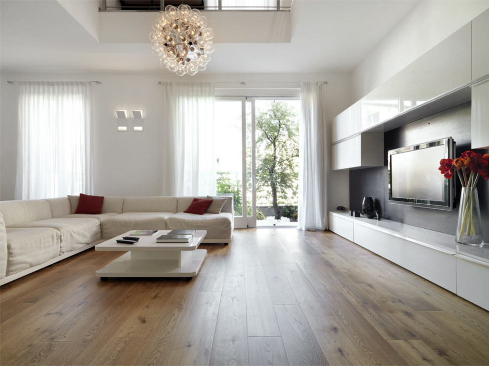 Modern inredning av ett stort allrum med öppen planlösning, med vita väggar, ljust trägolv och en väggmonterad TV