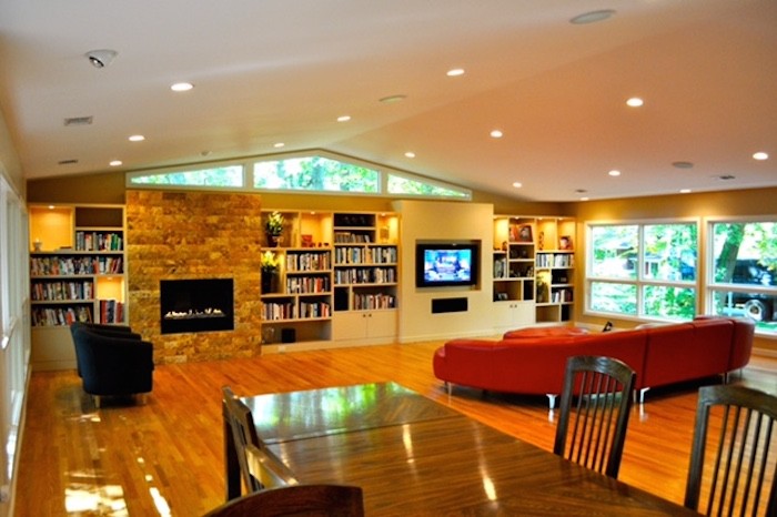 Exemple d'un grand salon moderne ouvert avec parquet clair, une cheminée standard, un manteau de cheminée en pierre, un téléviseur encastré et un sol marron.
