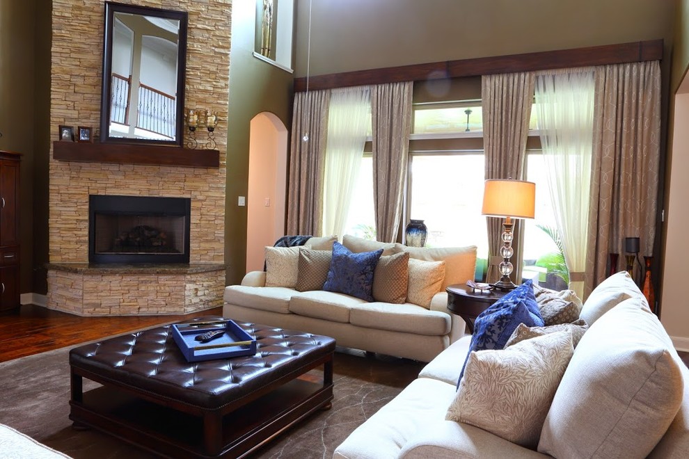 Exemple d'un grand salon chic ouvert avec un mur vert, parquet foncé, une cheminée standard, un manteau de cheminée en pierre, aucun téléviseur, une salle de réception et un sol marron.