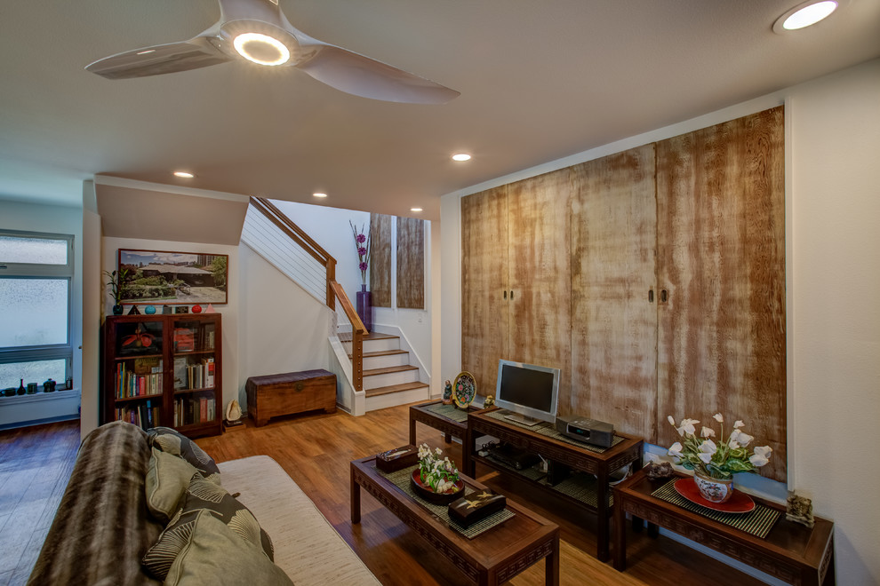 Modernes Wohnzimmer ohne Kamin mit weißer Wandfarbe, braunem Holzboden und freistehendem TV in Hawaii